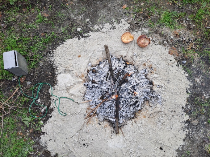 An overhead image of a circle of sand with a burning area in the middle.